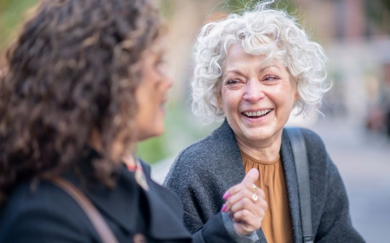 Two women smiling at Women's health naturopath consultations discussing hormone balance, menopause perimenopause and low energy.