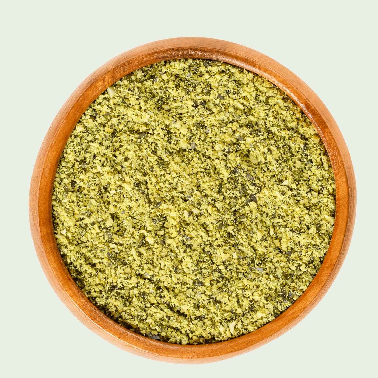 Wooden bowl filled with green Australian pumpkin seed meal on a light gray background