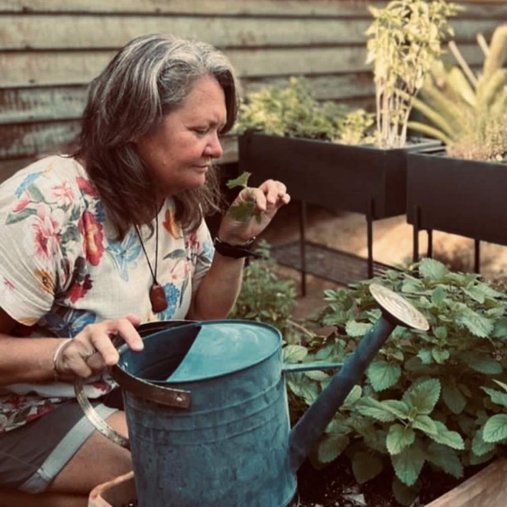 Contact Naturopath Gabby Scott from Sunshine House of Wellness watering plants on her property