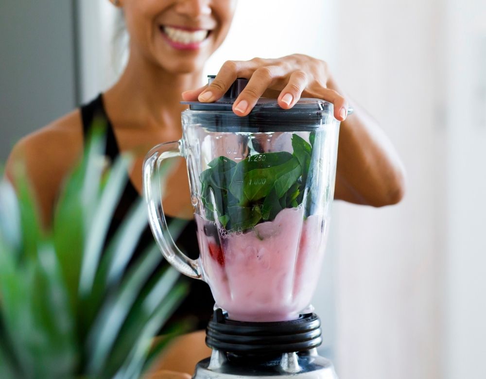 Smiling woman blending smoothie with hydrolysed collagen peptides — easy daily routine for skin and gut health.