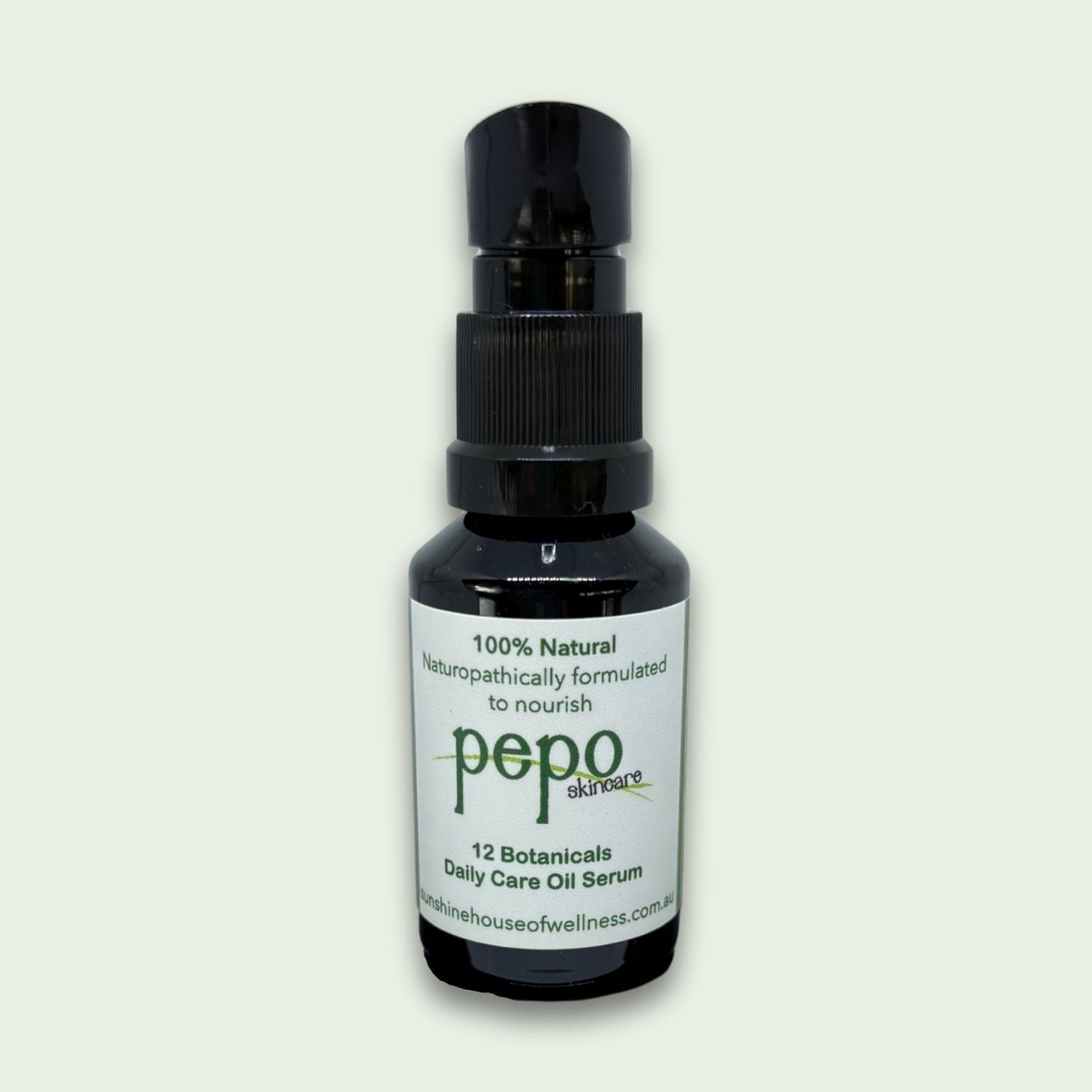 Black bottle of Pepo 12 Botanicals Daily Care Serum, natural skincare on a light gray background