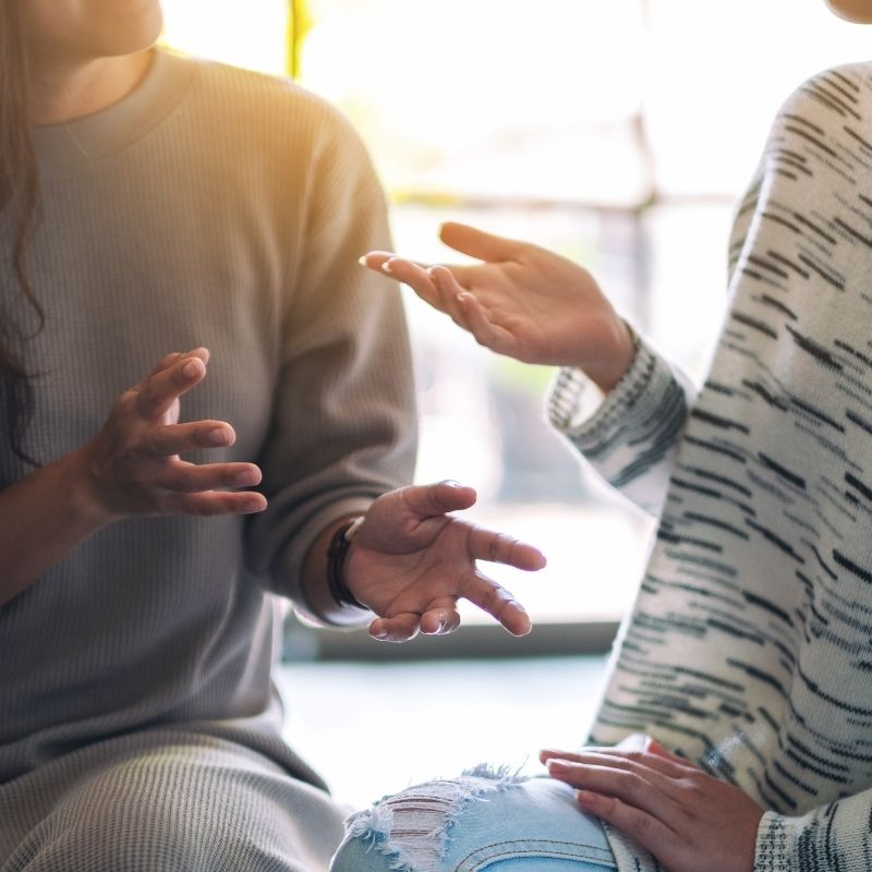 Two women engaged in a naturopath consultation for women's health with their hands gesturing.