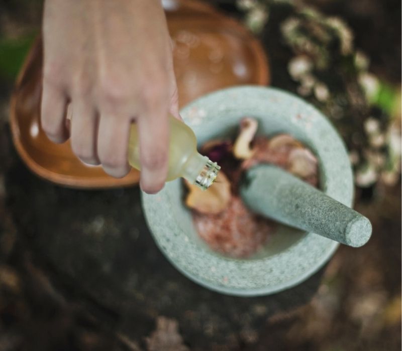Nauturopath's hand mixing herbal medicine ingredients in mortar and pestle on Sunshine Coast Hinterlands wellness clinic