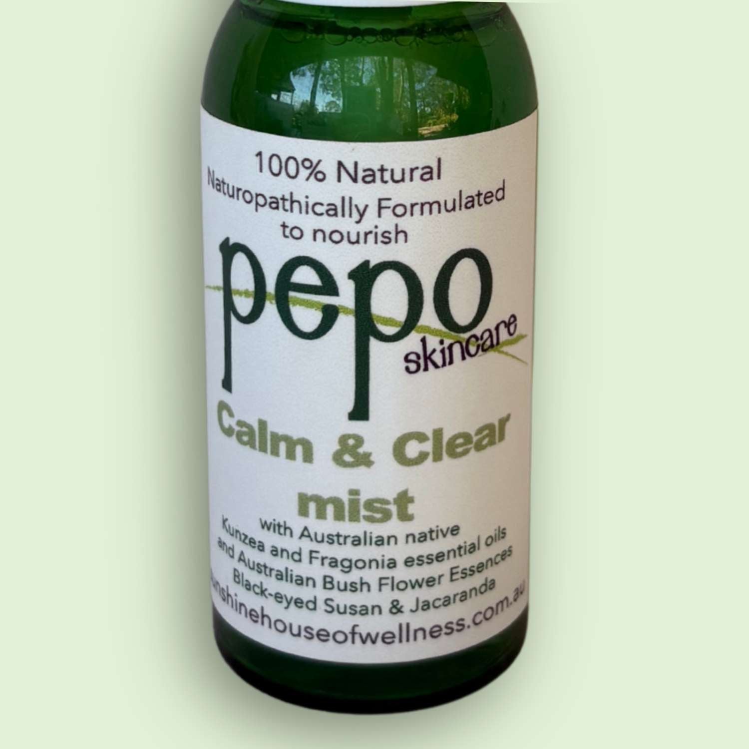 Green spray bottle labeled 'Pepo Skincare, Calm and Clear Mist' on light green background