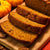 Sliced pumpkin bread made from Australian pumpkin seed meal on a wooden board with pumpkins in the background.